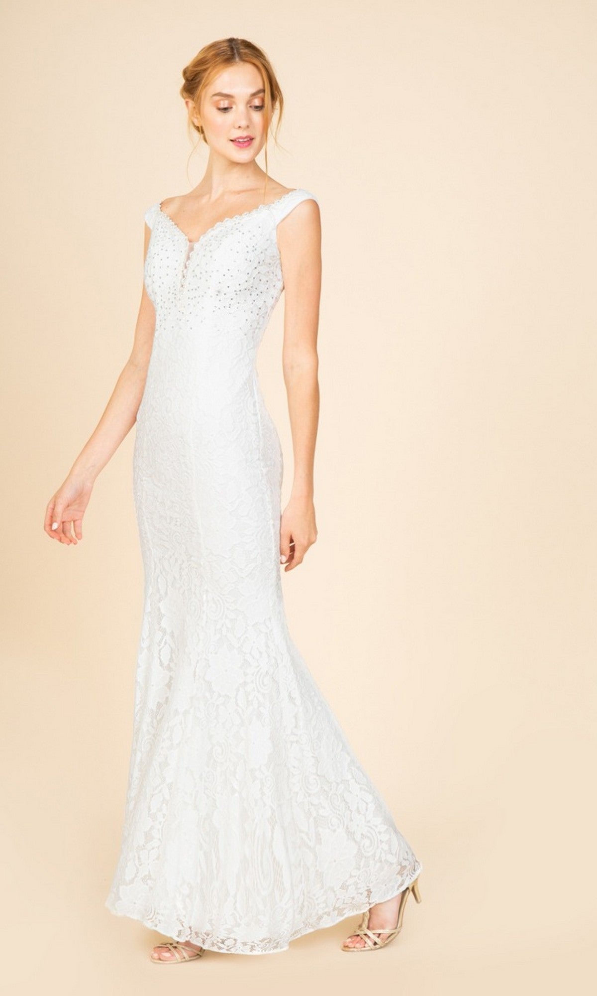 A woman in the Eureka 8050 long prom dress—an off-white, floor-length lace gown with a fitted bodice and subtle bead accents—poses against a plain beige background.